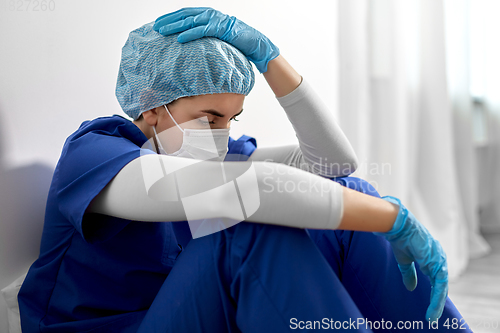 Image of sad doctor or nurse in face mask holding to head