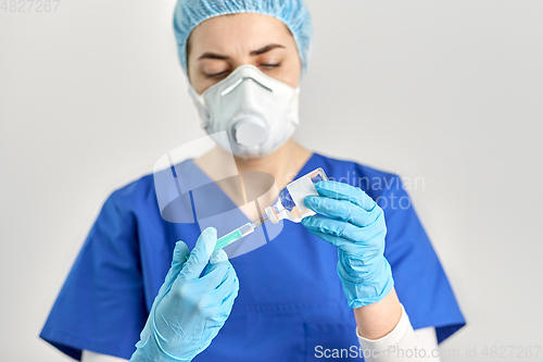 Image of doctor in face mask with syringe and medicine