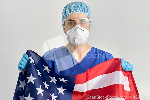 Image of doctor in goggles and mask holding flag of america