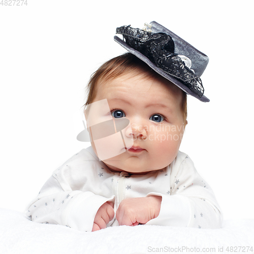 Image of beautiful baby girl in fancy hat on white blanket