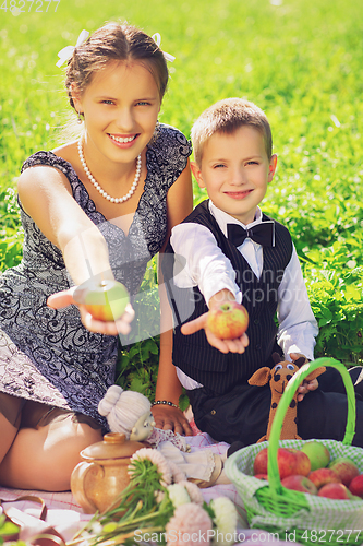 Image of Little boy and teen age girl having picnic outdoors