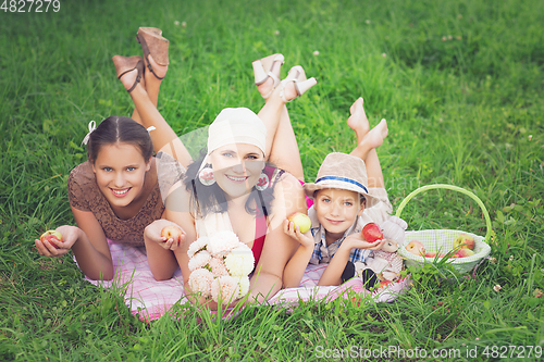 Image of mother with two kids having picnic outdoors