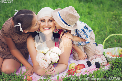 Image of mother with two kids having picnic outdoors