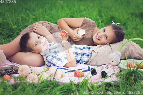 Image of Little boy and teen age girl having picnic outdoors