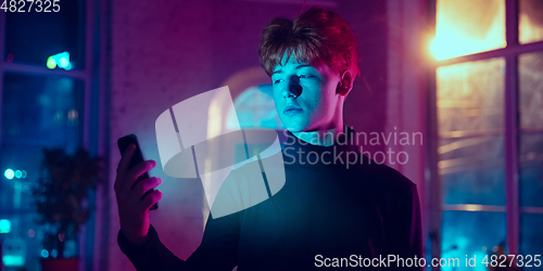 Image of Cinematic portrait of handsome young man in neon lighted interior