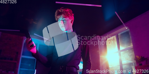 Image of Cinematic portrait of handsome young man in neon lighted interior