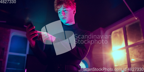 Image of Cinematic portrait of handsome young man in neon lighted interior