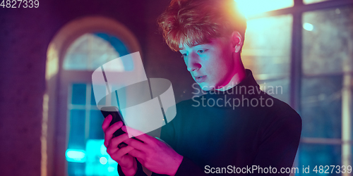 Image of Cinematic portrait of handsome young man in neon lighted interior