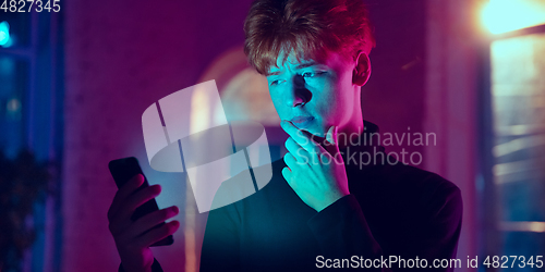 Image of Cinematic portrait of handsome young man in neon lighted interior