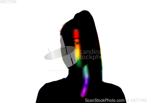 Image of Dramatic portrait of a girl in the dark on white studio background with rainbow colored line