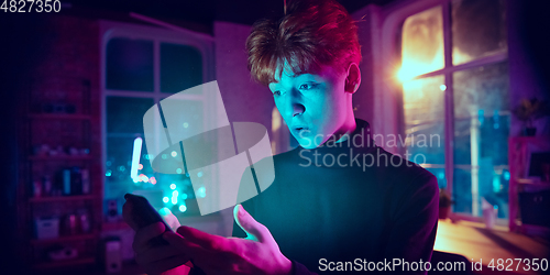 Image of Cinematic portrait of handsome young man in neon lighted interior