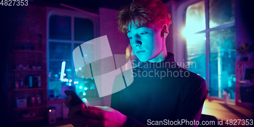 Image of Cinematic portrait of handsome young man in neon lighted interior