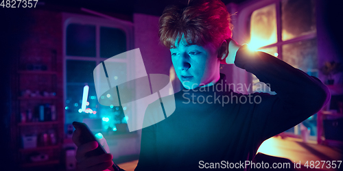 Image of Cinematic portrait of handsome young man in neon lighted interior