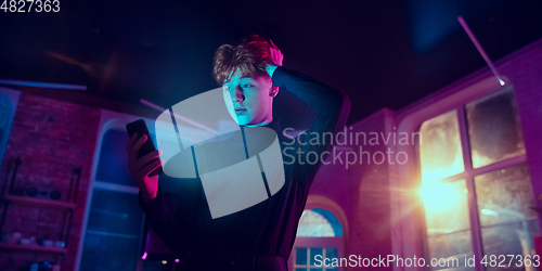 Image of Cinematic portrait of handsome young man in neon lighted interior