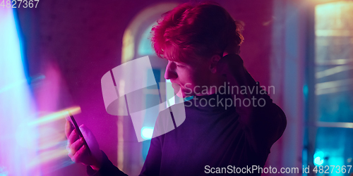 Image of Cinematic portrait of handsome young man in neon lighted interior