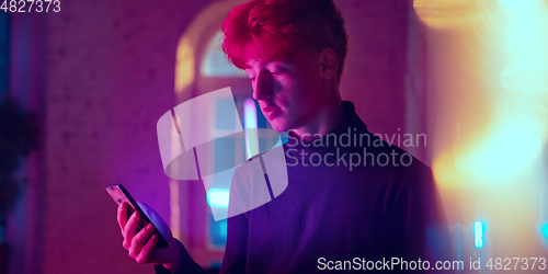 Image of Cinematic portrait of handsome young man in neon lighted interior