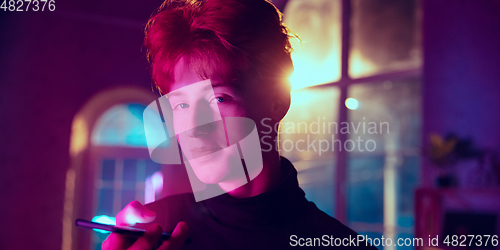 Image of Cinematic portrait of handsome young man in neon lighted interior