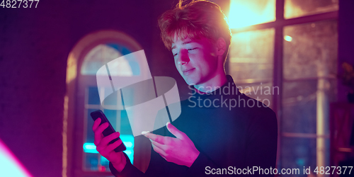 Image of Cinematic portrait of handsome young man in neon lighted interior