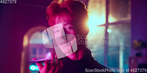 Image of Cinematic portrait of handsome young man in neon lighted interior