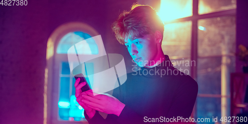 Image of Cinematic portrait of handsome young man in neon lighted interior