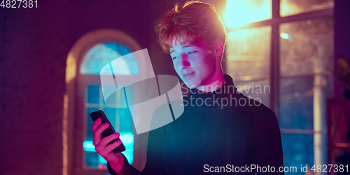 Image of Cinematic portrait of handsome young man in neon lighted interior