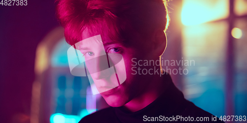 Image of Cinematic portrait of handsome young man in neon lighted interior