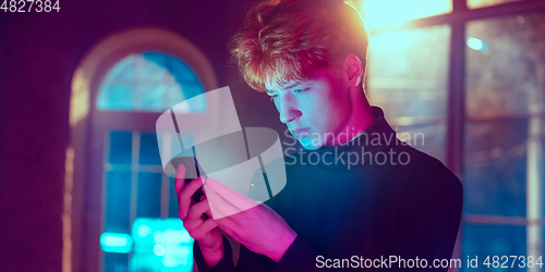 Image of Cinematic portrait of handsome young man in neon lighted interior