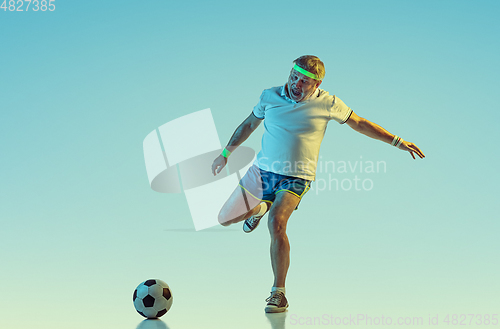 Image of Senior man playing football in sportwear on gradient background and neon light