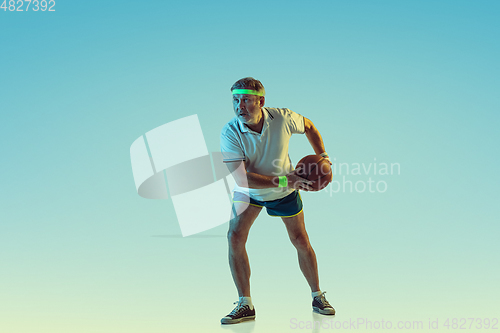 Image of Senior man playing basketball in sportwear on gradient background and neon light