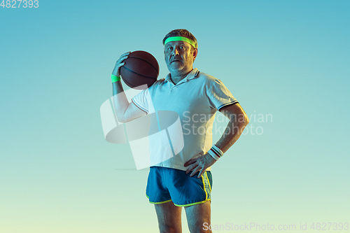 Image of Senior man playing basketball in sportwear on gradient background and neon light