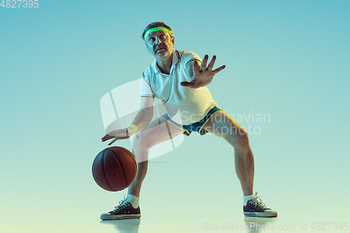 Image of Senior man playing basketball in sportwear on gradient background and neon light