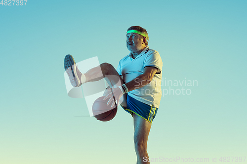 Image of Senior man playing basketball in sportwear on gradient background and neon light