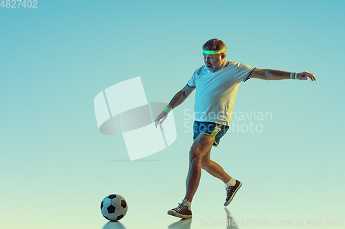 Image of Senior man playing football in sportwear on gradient background and neon light