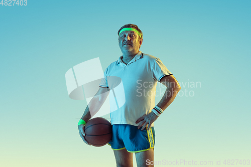 Image of Senior man playing basketball in sportwear on gradient background and neon light