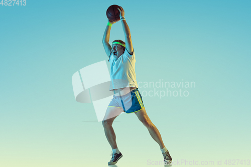 Image of Senior man playing basketball in sportwear on gradient background and neon light