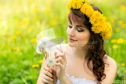 Image of beautiful girl with dandelion flowers in green field
