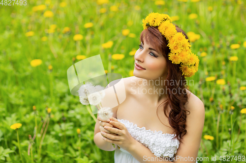 Image of beautiful girl with dandelion flowers in green field