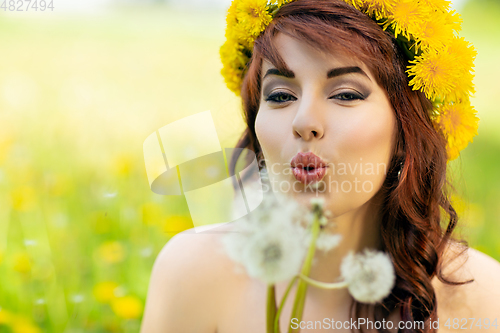 Image of beautiful girl with dandelion flowers in green field