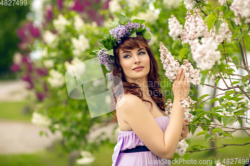 Image of beautiful girl in purple dress with lilac flowers
