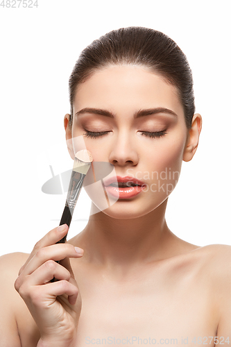 Image of girl applying foundation on face isolated on white