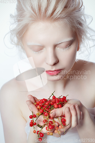 Image of beautiful albino young woman with red berries