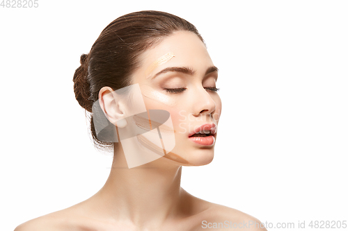 Image of girl applying foundation on face isolated on white