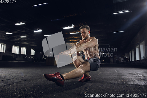 Image of Young healthy male athlete doing exercises in the gym