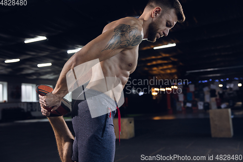 Image of Young healthy male athlete doing exercises in the gym