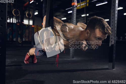 Image of Young healthy male athlete doing exercises in the gym