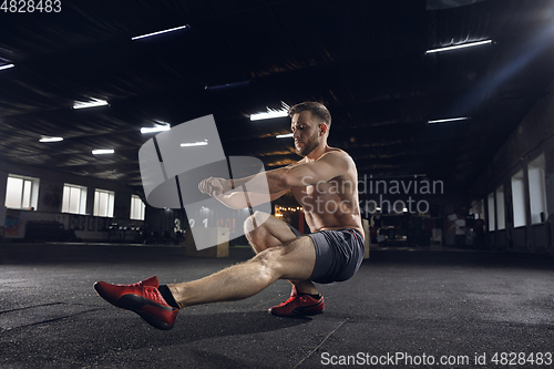 Image of Young healthy male athlete doing exercises in the gym