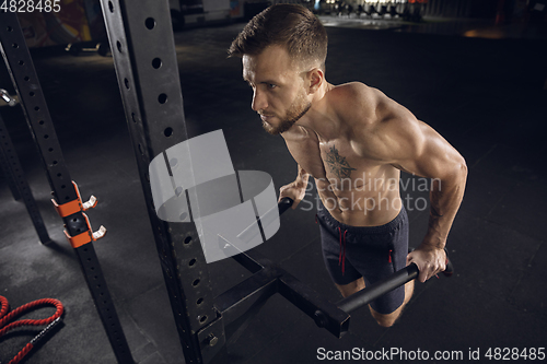 Image of Young healthy male athlete doing exercises in the gym