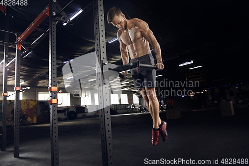 Image of Young healthy male athlete doing exercises in the gym