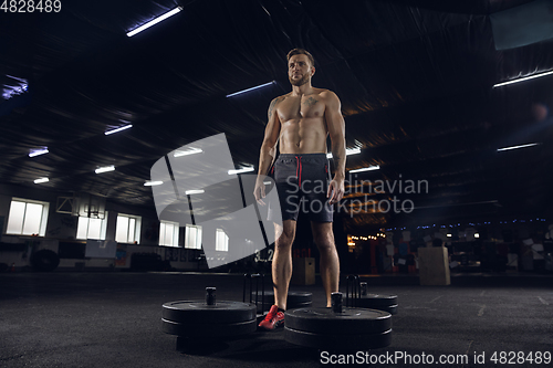 Image of Young healthy male athlete doing exercises in the gym