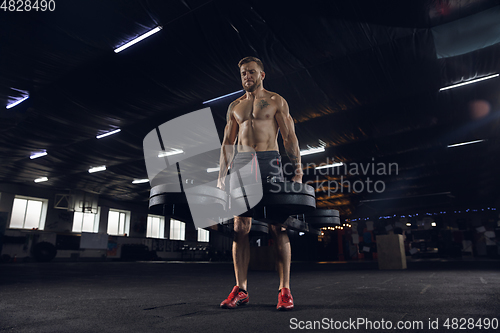 Image of Young healthy male athlete doing exercises in the gym